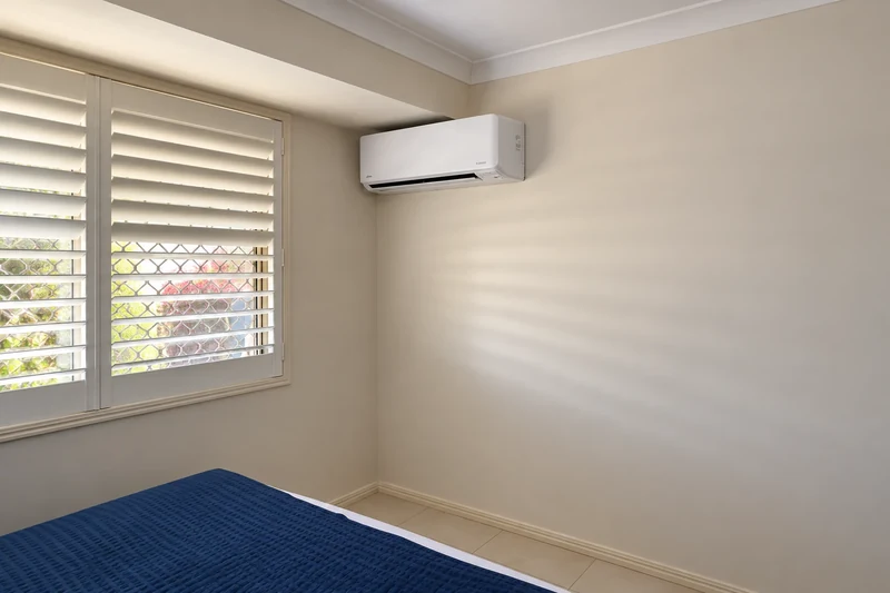 A wall-mounted split system air conditioner in a bedroom