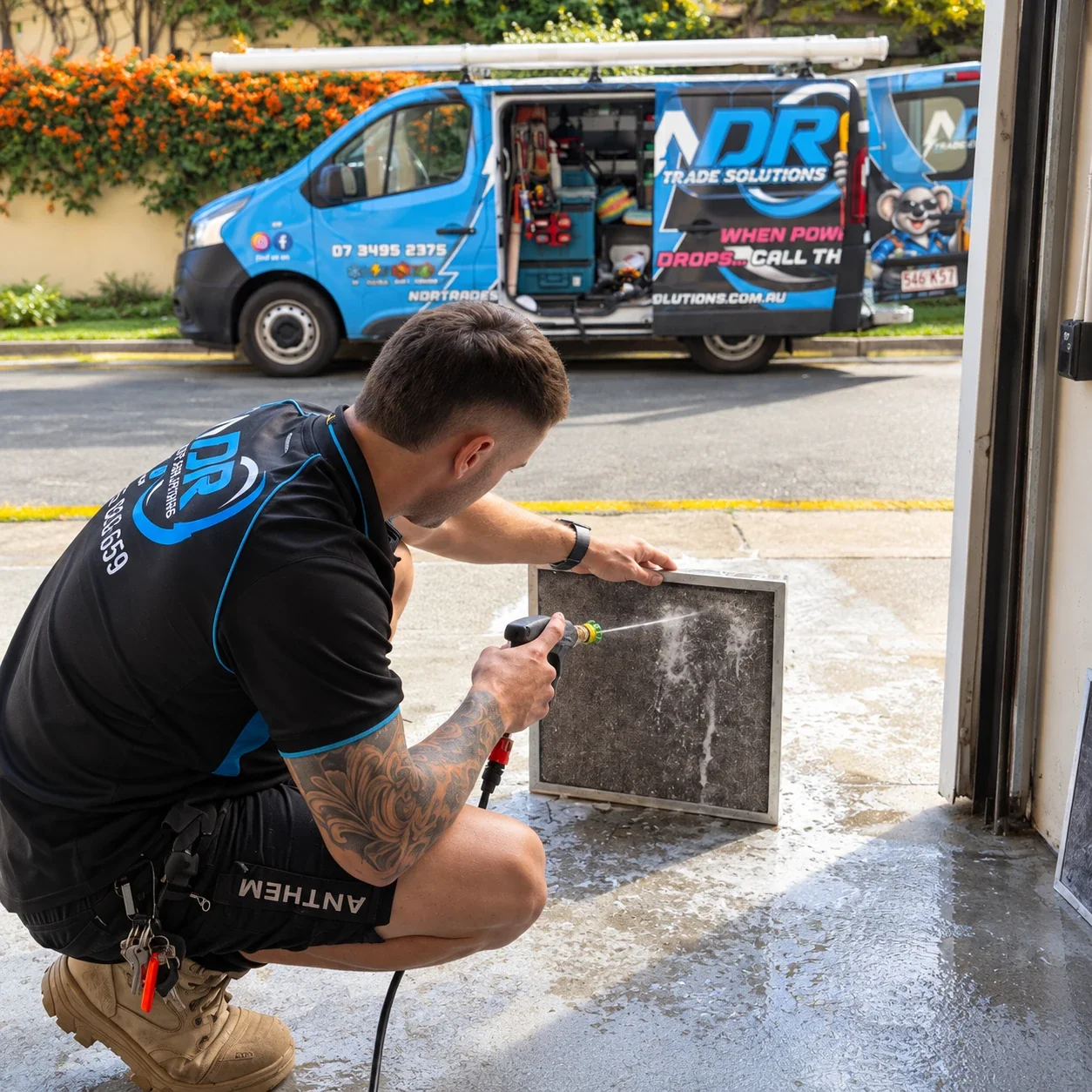 An NDR technician cleaning an air-conditioning filter